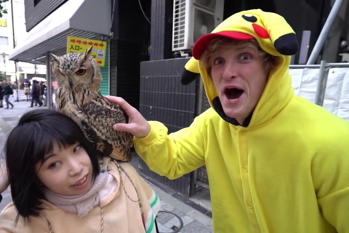 Logan Paul in Pikachu costume petting an owl sitting on a Japanese woman’s shoulder