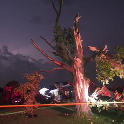 Lightning lights up the sky behind a mangled tree and a house on Bray Road north of Birch Run Road in Tuscola County's Arbela Township that were destroyed by a tornado that swept through Saginaw and Tuscola Counties Monday night, June 22, 2015. 
