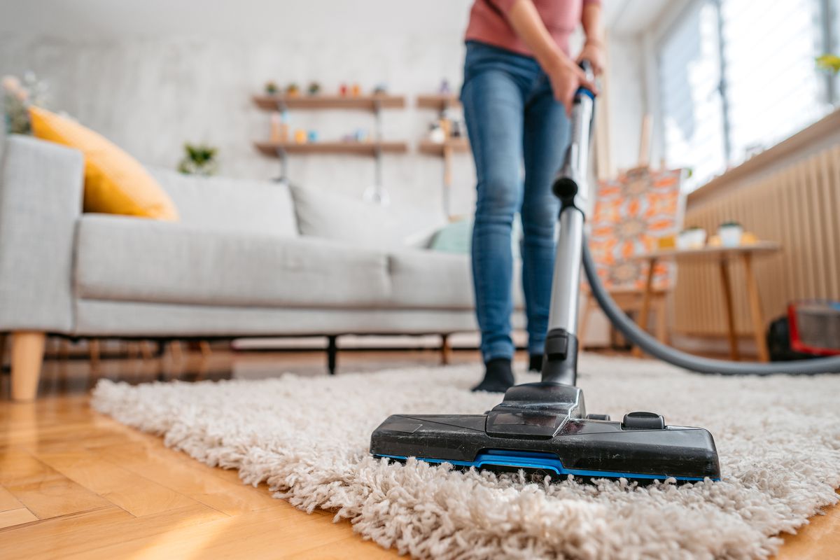 Person vacuuming rug at home