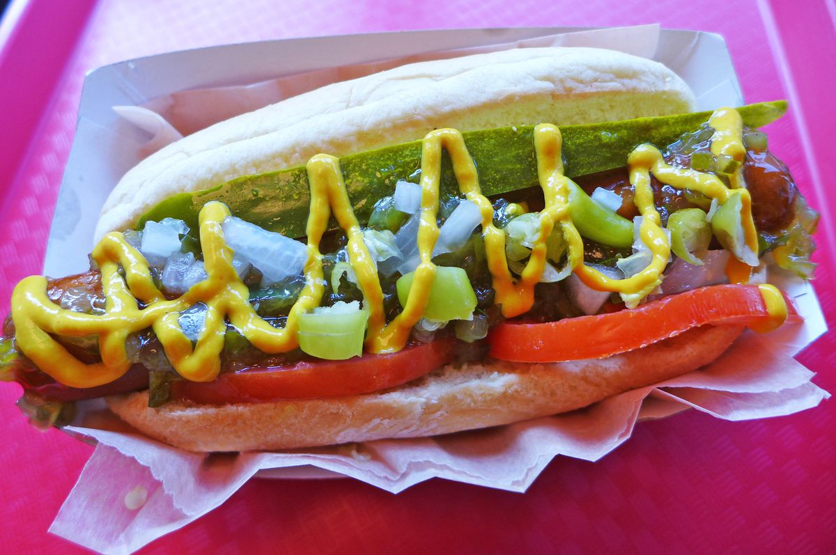 A vegan hot dog topped with mustard, onions, and other accoutrements