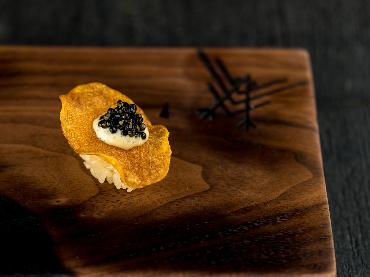 Potato chip nigiri with grilled ramp aioli and Ossetra caviar, placed next to the Robin logo