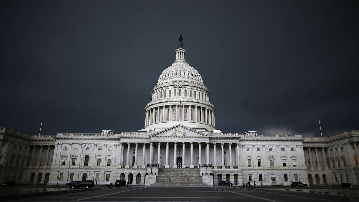 The US Capitol building with dark clouds behind it.