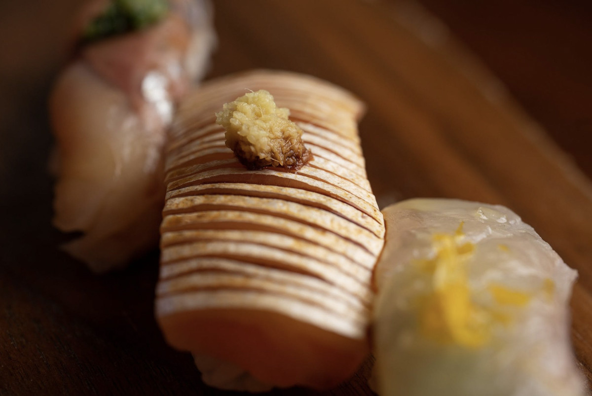 A close up shot of nigiri, thinly sliced and topped with ginger.