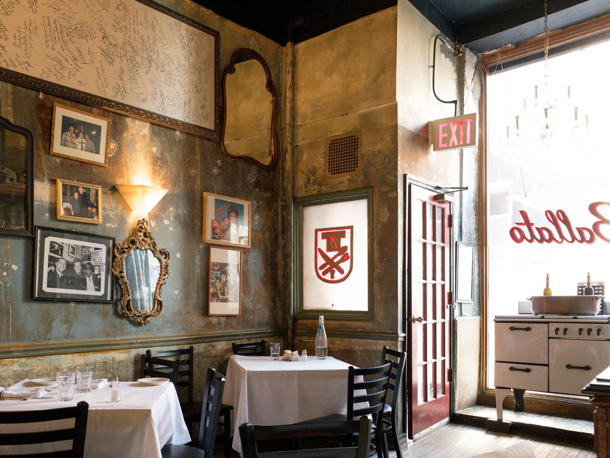 Photos and paintings hang on the wall of a white tablecloth Italian restaurant, Emilio’s Ballato.