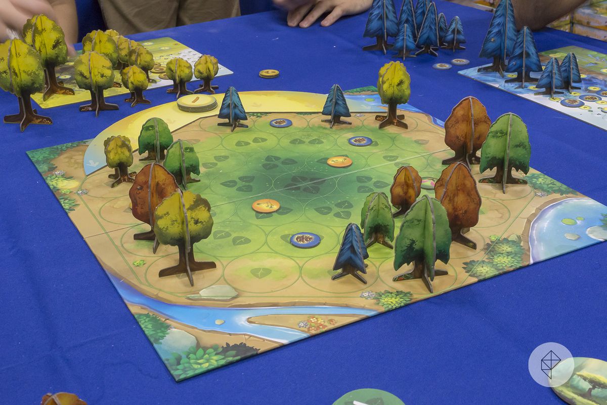 Green, yellow, brown and blue trees made of cardboard spring up around a brightly-colored forest clearing.
