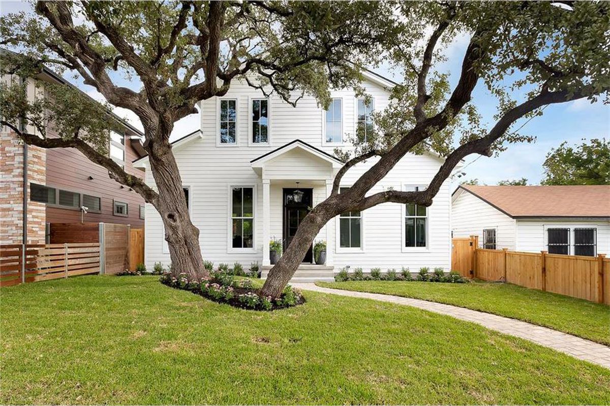 Tall, two-story white frame house behind live oak tree