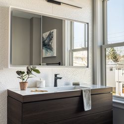 Textured white wall tile makes a crisp backdrop to the wall-hung vanity in the second-floor hallway bath. 