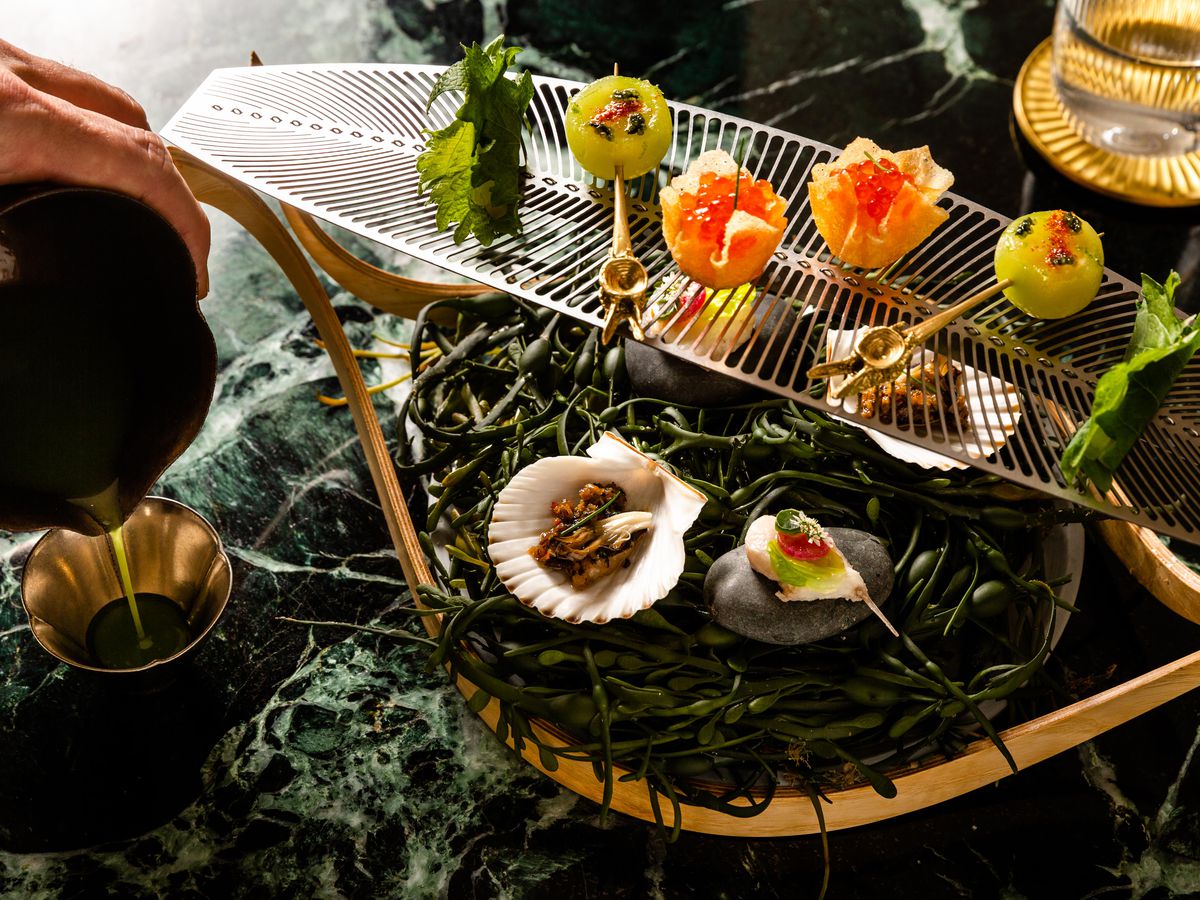 Assorted fluke preparations, in green shiso wrappers, in scallop shells, and in pastry shells, sit on a two-tiered platter