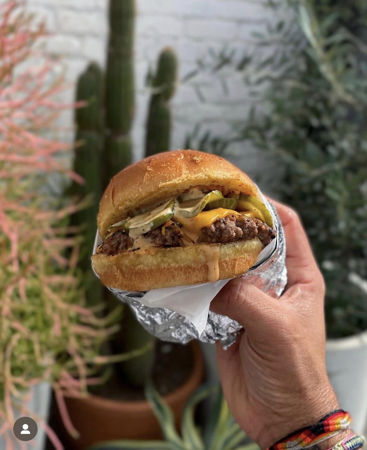 A hand holds a burger with cheese from SolRad burger in Montebello, California.