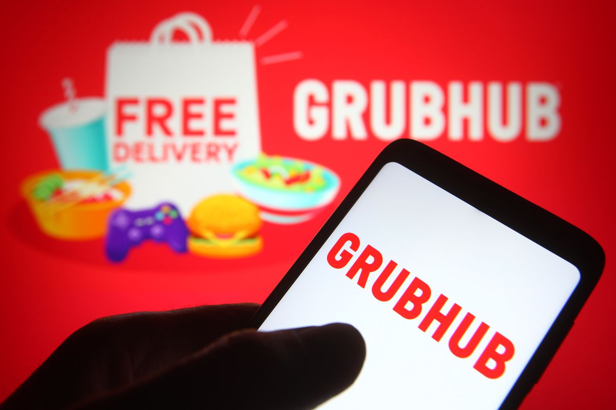 In this photo illustration, a hand swipes on the Grubhub logo on a phone.