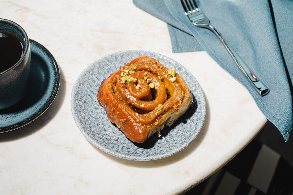 A sticky bun is topped with crushed pistachio pieces.