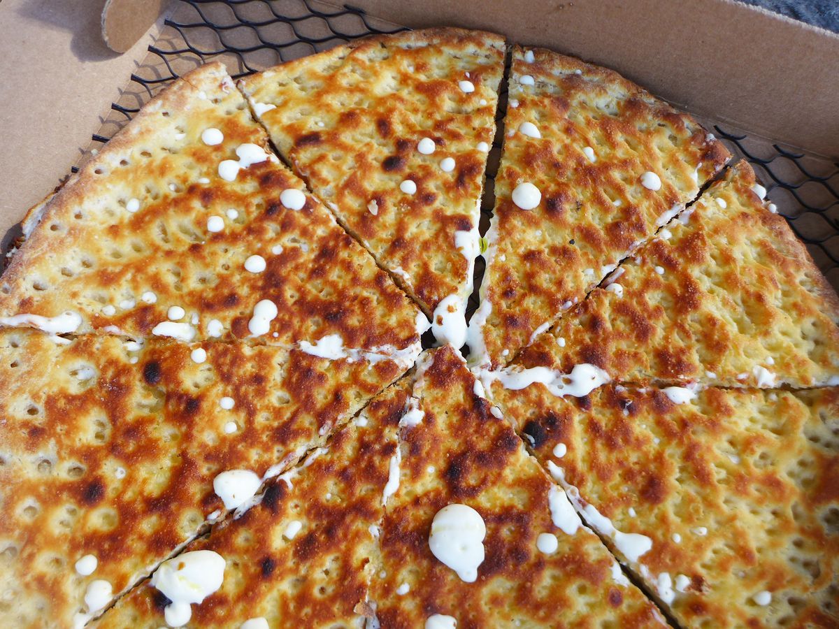 Three quarters view of a nicely browned pie with spots of white cheese oozing out a series of holes.