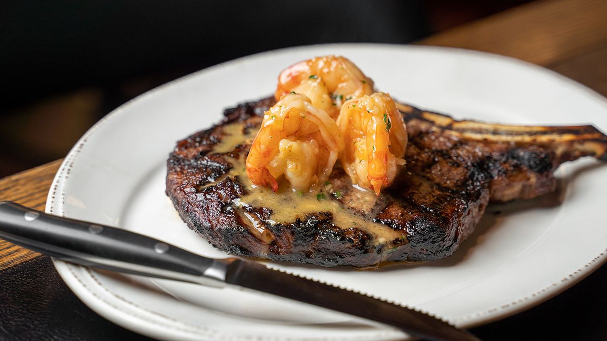 A steak topped with shrimp in a creamy sauce.