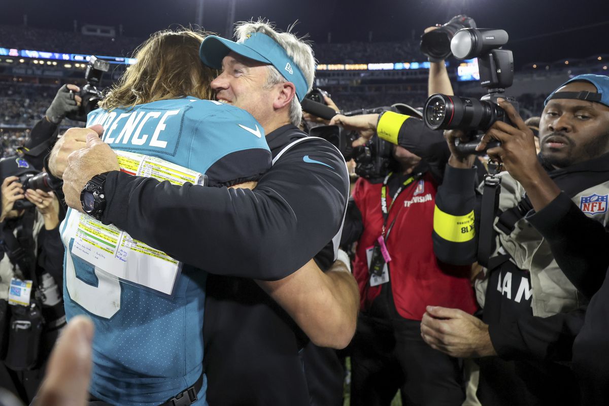 Head coach Doug Pederson of the Jacksonville Jaguars hugs Trevor Lawrence #16 of the Jacksonville Jaguars after their 20-16 playoff clinching win against the Tennessee Titans at TIAA Bank Field on January 07, 2023 in Jacksonville, Florida.