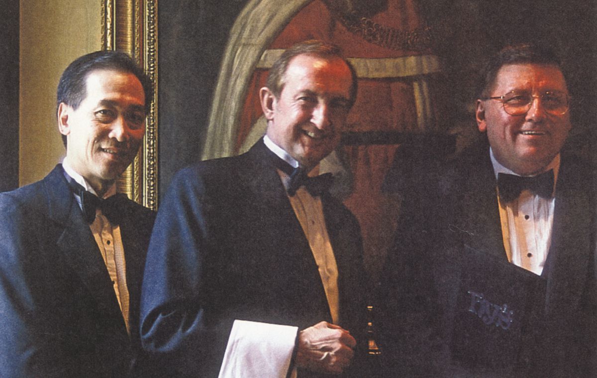 Three servers in tuxedos in an old photograph. 