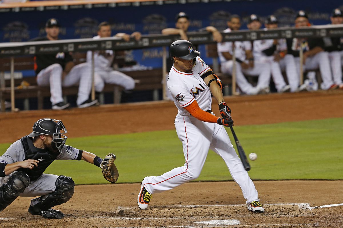 Giancarlo Stanton hits a single during the third inning against the Colorad...