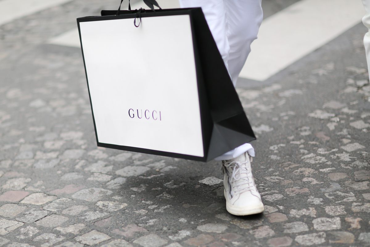 A person holding a Gucci shopping bag