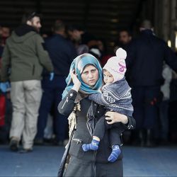 A woman carrying a baby disembarks from a ferry after her arrival along with other migrants and refugees at the port of Elefsina, west of Athens, on Sunday, March 20, 2016. Sunday is the day an agreement between the European Union and Turkey on ending illegal migration goes into effect — but its implementation still remains uncertain. Greek authorities say they're not sure any migrants entering Greece will be processed and turned back before Monday. 
