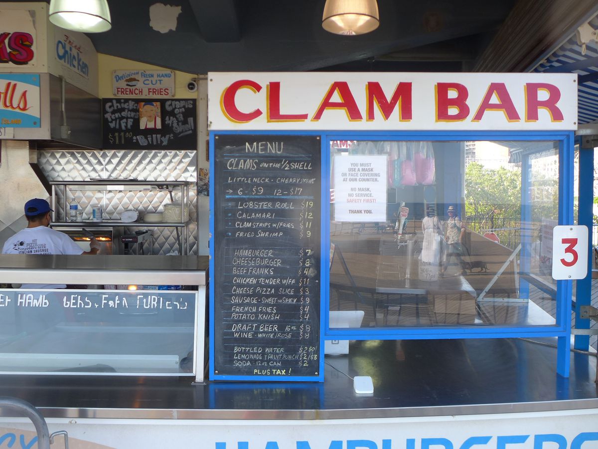 A counter with a chalkboard menu and sign that reads Clam Bar.