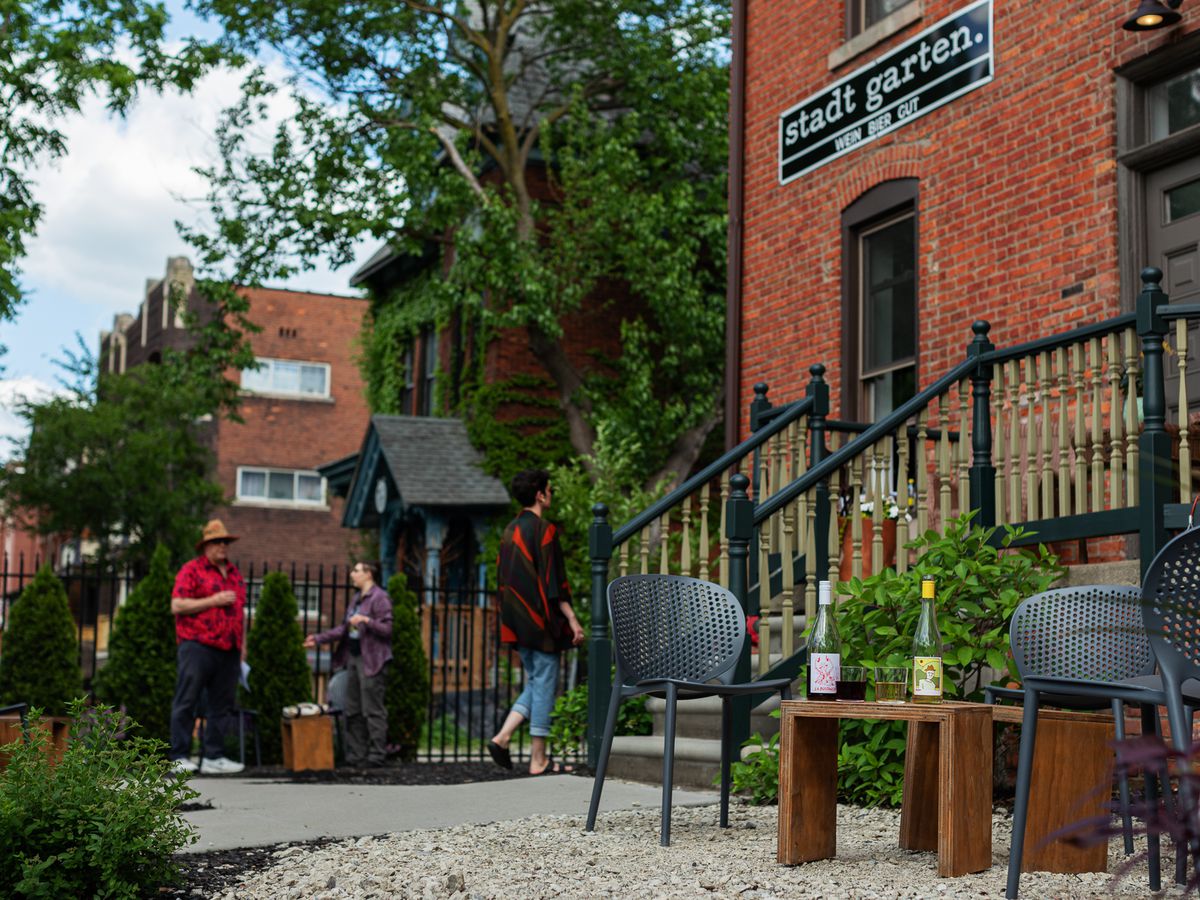 A garden patio with black seating, steps, banisters, a brick building with a sign that says Stadt Garten Wein Bier Gut at Stadt Garten in Midtown, Detroit, Michigan.