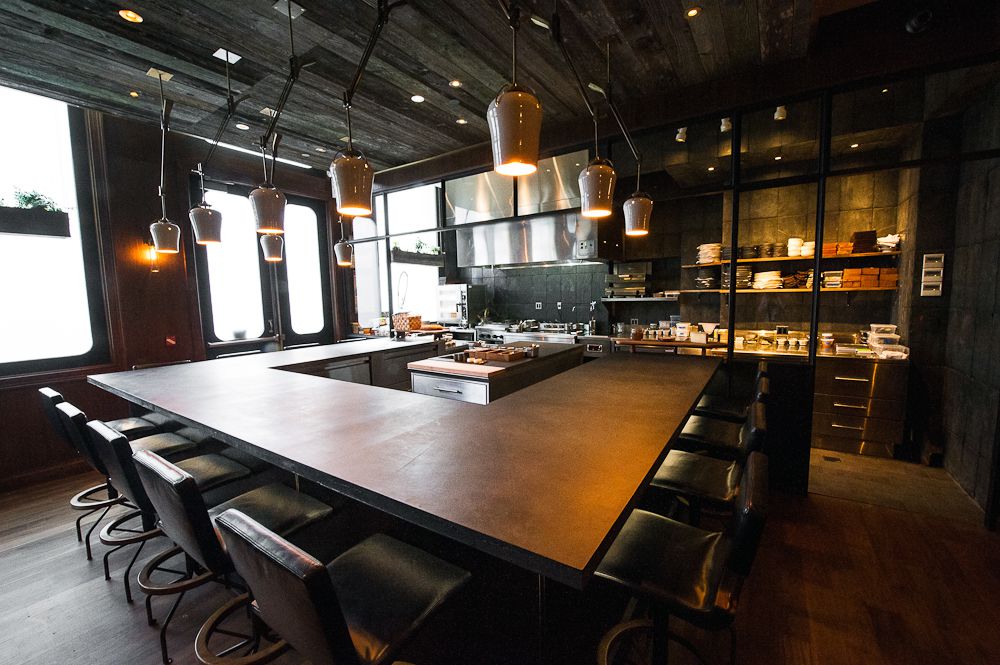 A U-shaped wooden table with dark wood furniture and hanging light fixtures.