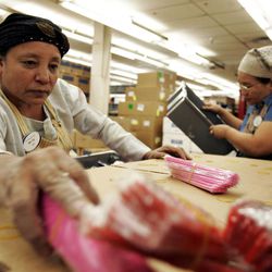 Mara Moryon, left, grabs a bundle of combs to unwrap and put into hygiene kits for victims of Hurricane Ike as Than Hia, right, stacks containers at the LDS Humanitarian Center in Salt Lake City on Friday, September 12, 2008.