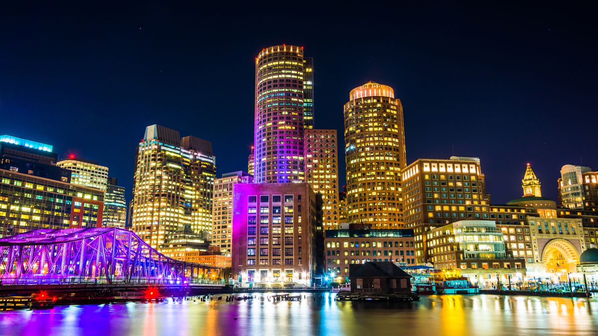 A nighttime view of the Boston skyline, focusing on a slice of the Financial District