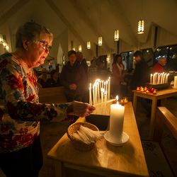 Mary Johnson lights a candle at the All Saints Episcopal Church as those gathered honor lives lost to gun violence at an interfaith vigil in Salt Lake City on Sunday, Dec. 9, 2018.