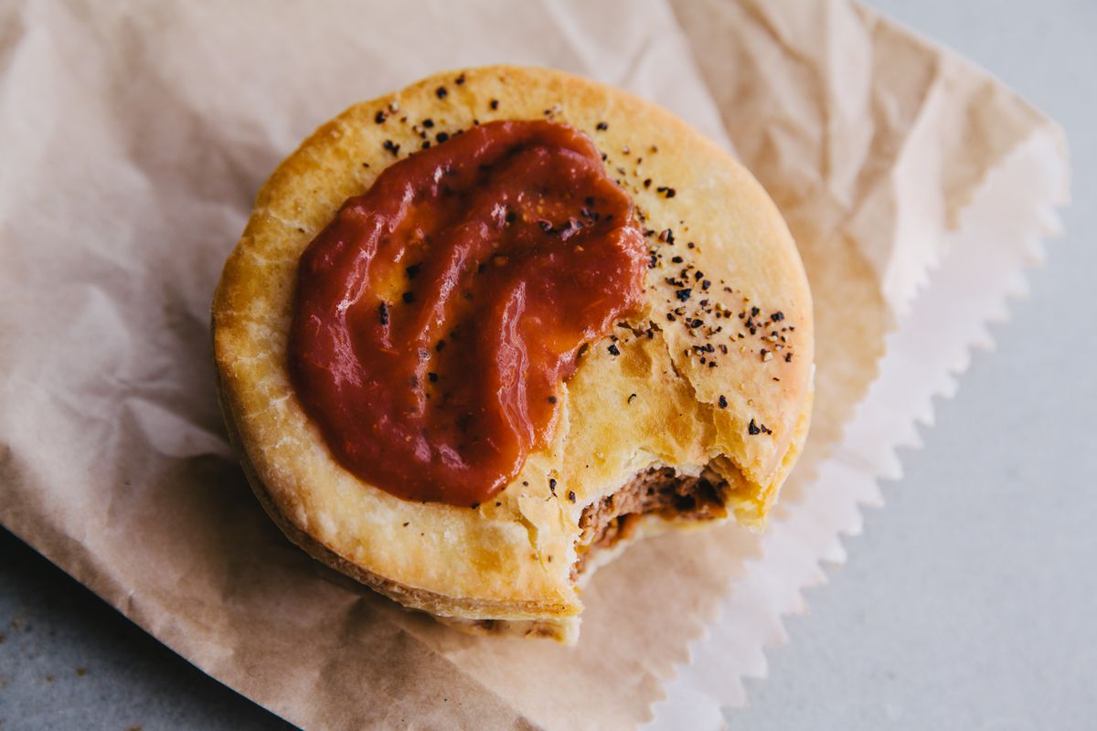 A smear of tomato sauce tops a classic meat pie with a single bite