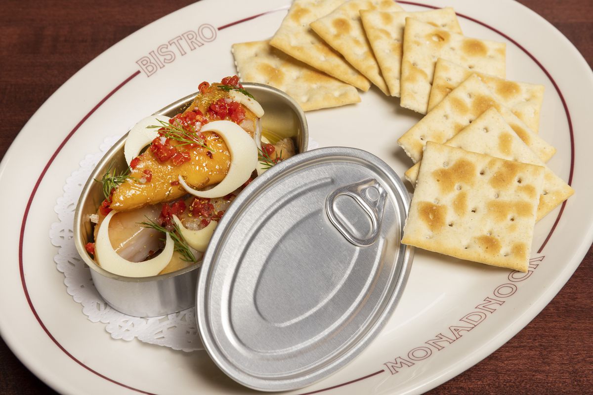 A small metal tin of smoked walleye beside saltine crackers.