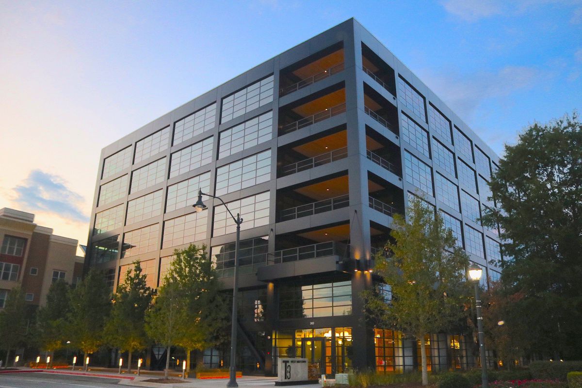 A ground-level view of the new office building, which stands seven stories and is wrapped in black metal and large windows.