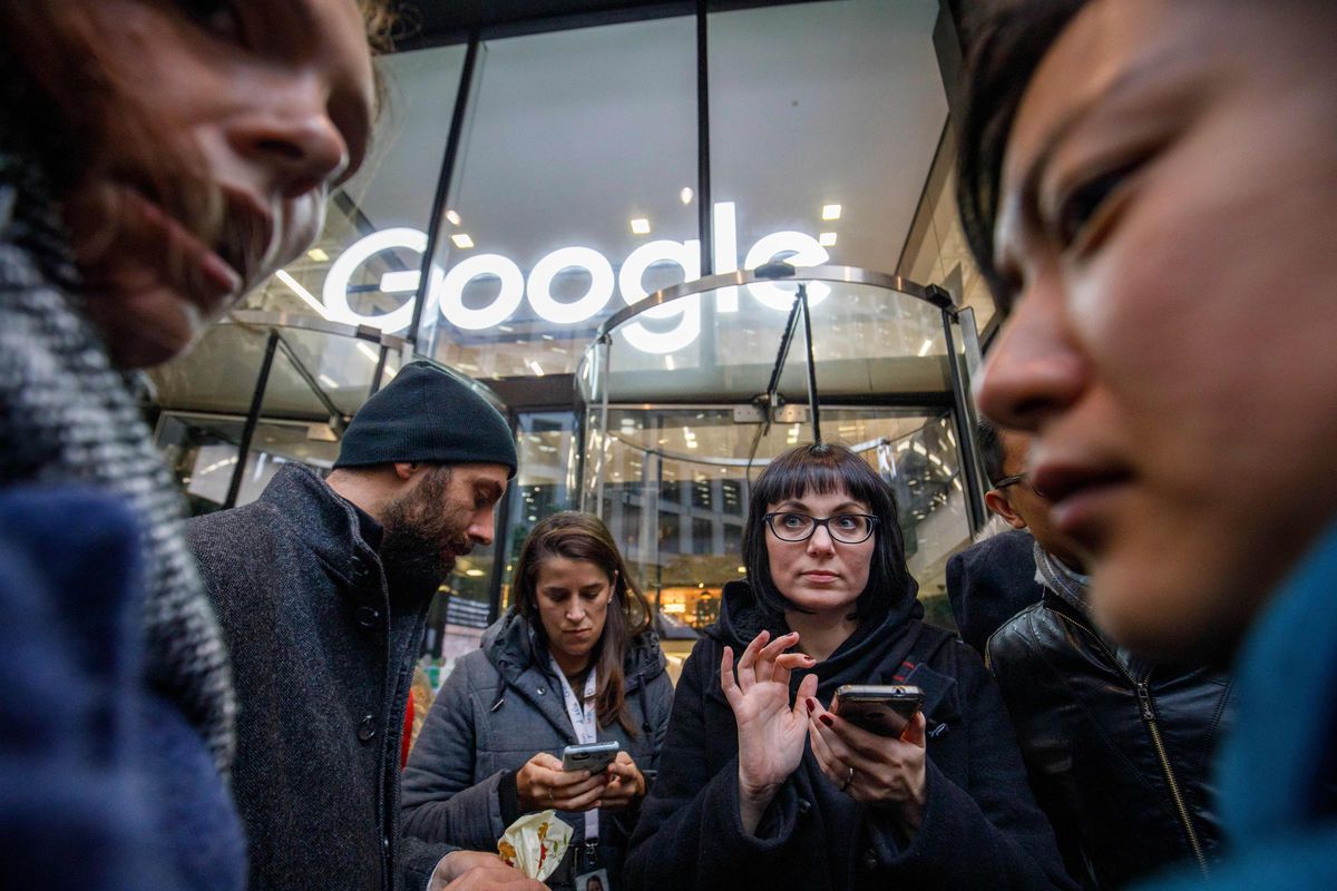A group of Google employees stands in front of a Google office building in London during a protest.