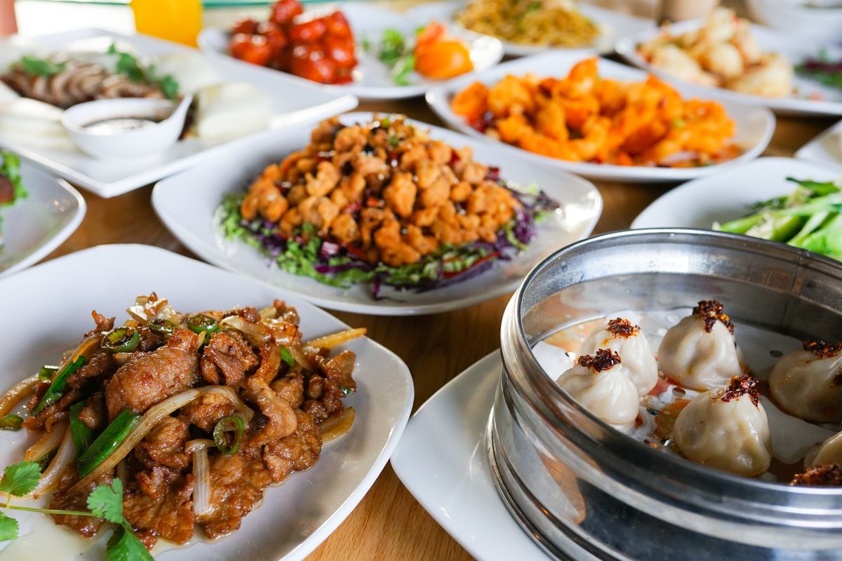 A Lao Sze Chuan spread of dumplings, stir fry, fried chicken pieces, and more.