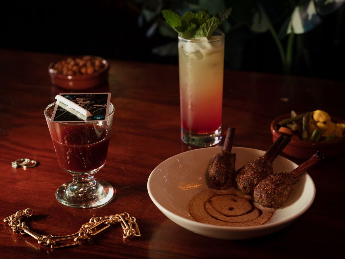 Two cocktails are artfully displayed next to a side dish of cinnamon kefta. 