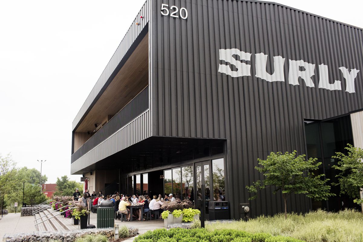 The black Surly building rises like a monolith over a small sidewalk patio with a table full of people