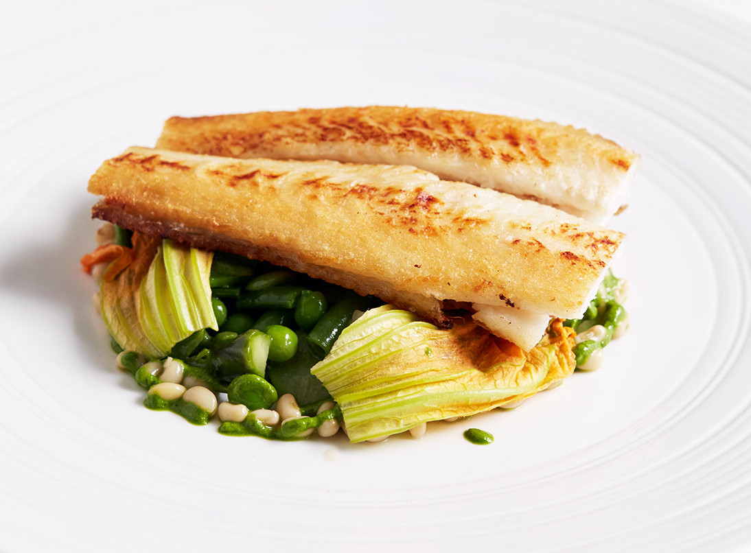 A fillet of sea bass on a mound of vegetables. 