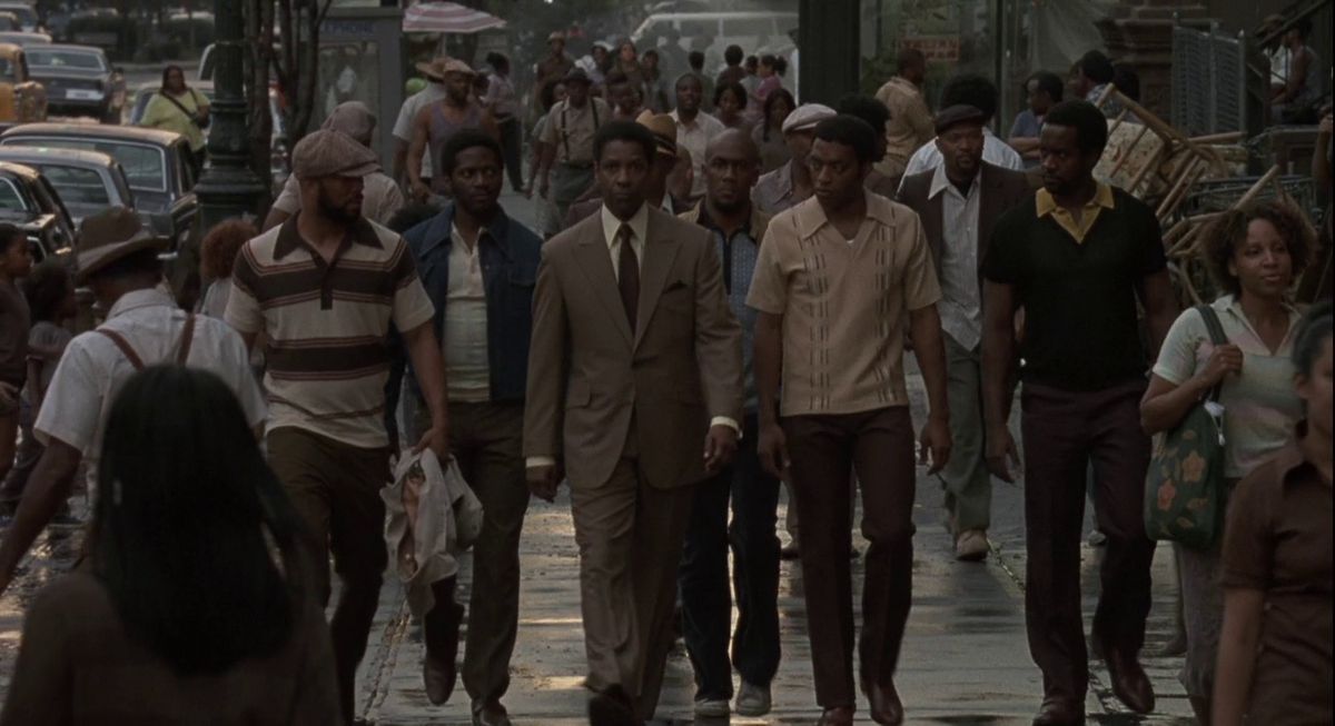 Denzel Washington as drug lord Frank Lucas walking down a street flanked by members of his criminal organization in American Gangster.