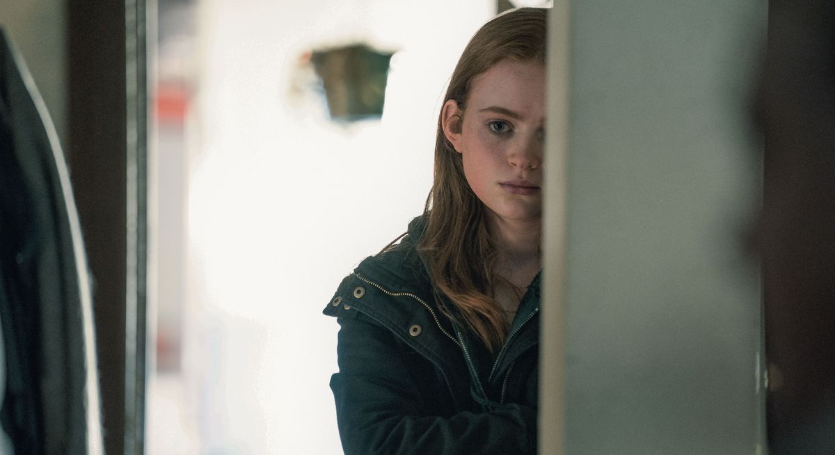 Charlie's 17-year-old daughter Ellie (Sadie Sink) stands half-shadowed by a doorway, looking sad, in The Whale