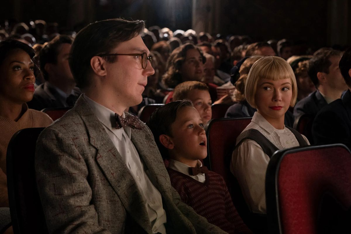 Two parents look at one another across the head of a young boy, who is mesmerized by something on a film screen.
