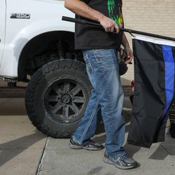 A man carries a "thin blue line" flag at a fundraiser and memorial car show and cruise at the Valley Fair Mall in West Valley City on Saturday, Nov. 12, 2016. The event was held in honor of Cody Brotherson, a West Valley City police officer who was killed in the line of duty.