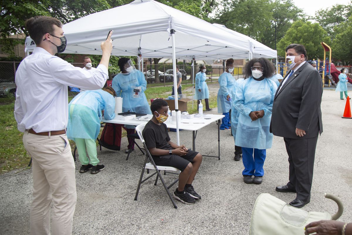 Gov. J.B. Pritzker takes a photo with medical personnel during a visit to a mobile COVID-19 testing station last July.
