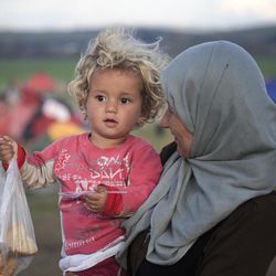 A child holds a food ration at the northern Greek border station of Idomeni, Friday, March 11, 2016. After nearly three days of rain, conditions in the refugee camp on the Greek-Macedonian where about 14,000 people are stranded have deteriorated significantly, with many of its residents struggling to re-pitch their small camping tents in slightly drier patches.