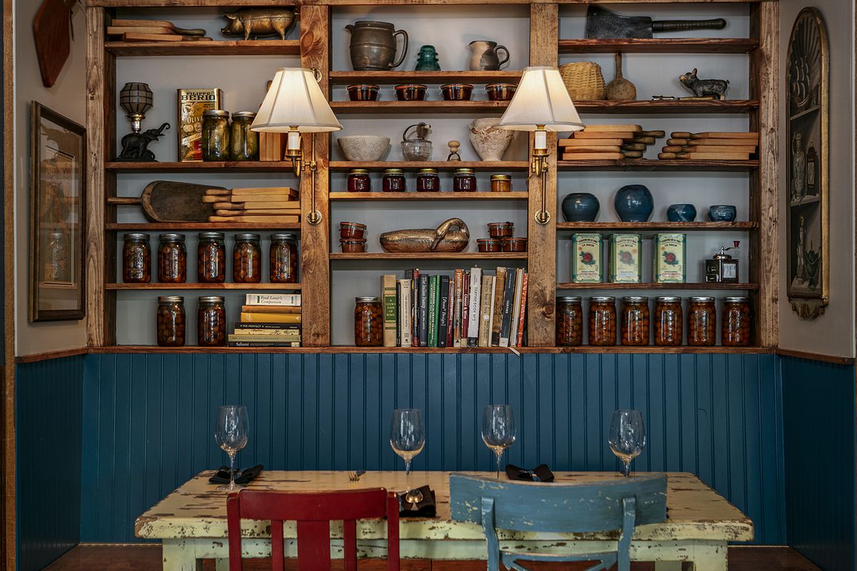Above a teal painted booth, a library wall looks down on a rustic table and mismatched chairs.
