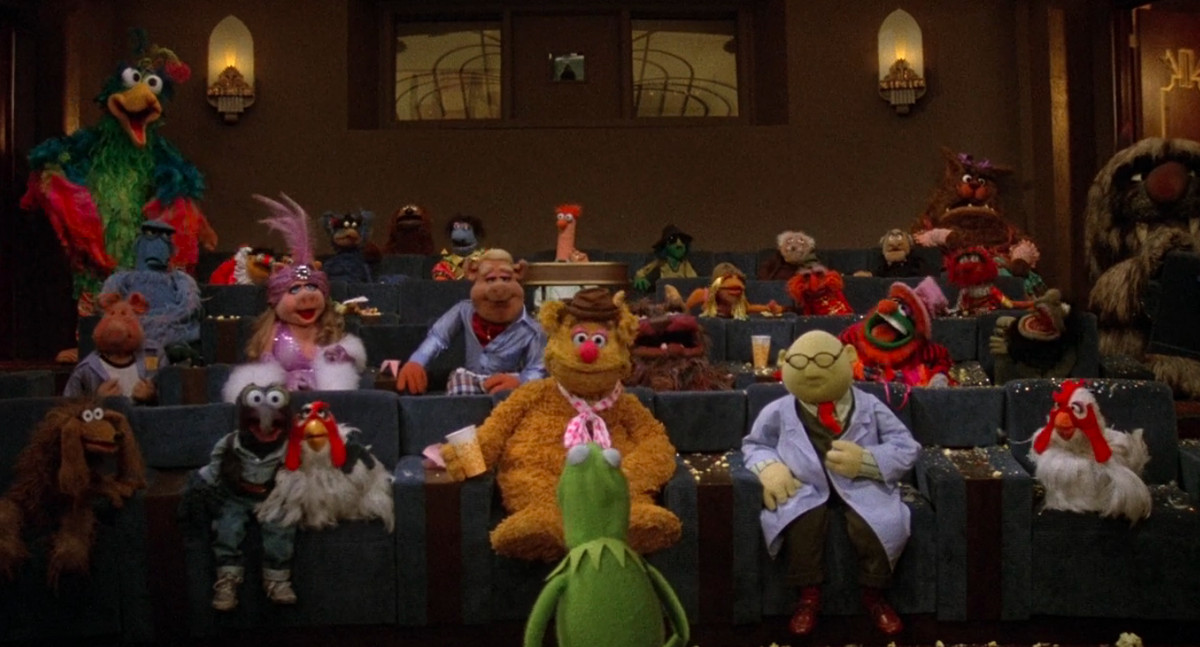 The Muppet movie cast sits in a screening room with Kermit leading the conversation