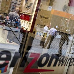 Pedestrians are reflected in the store window of a Verizon Wireless store near the New York Stock Exchange in lower Manhattan, Thursday, June 6, 2013, in New York. The National Security Agency is currently collecting the telephone records of millions of U.S. customers of Verizon under a top secret court order, said Britain's guardian newspaper said Wednesday. (AP Photo/John Minchillo)