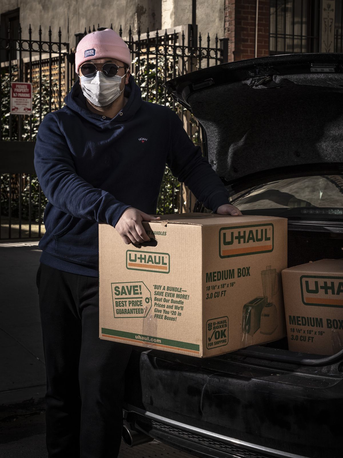 Delivery man and 886 owner Eric Sze wearing sunglasses and a face mask putting boxes of food in the back of a car