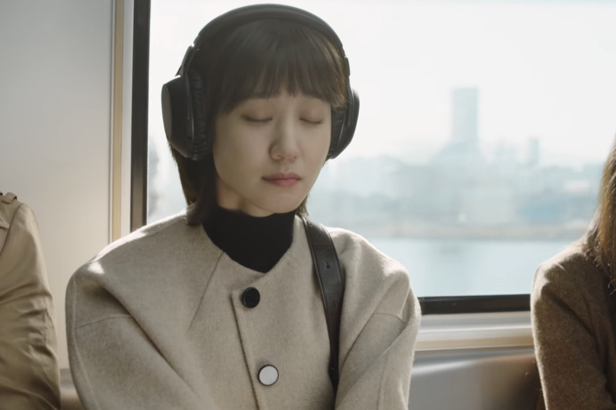 Woo Young-woo sitting on the train with her eyes closed listening to whale sounds in Extraordinary Attorney Woo