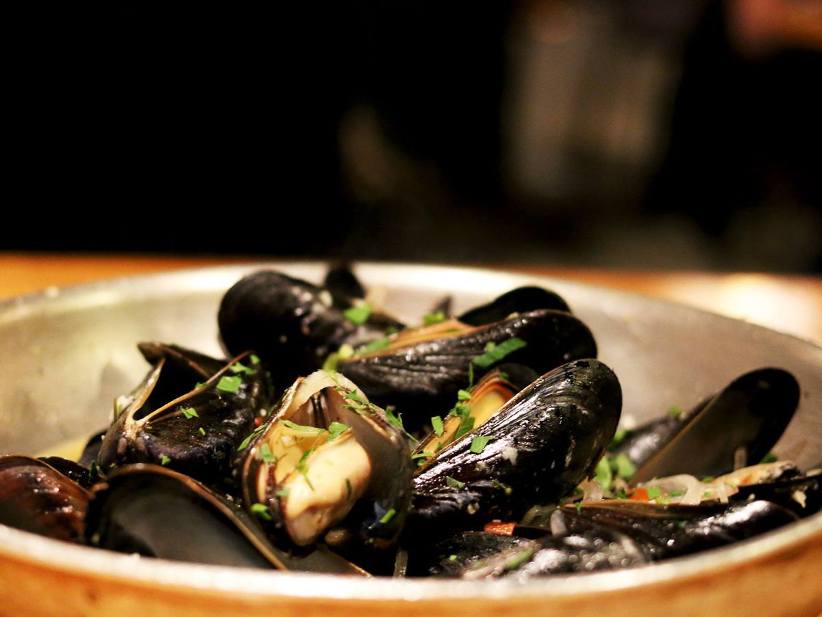 A silver pan is full of steamed mussels