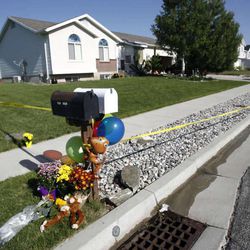 Flowers and stuffed animals are placed at the crime scene in West Point on Thursday, May 23, 2013. A 15-year-old boy arrested in connection with the deaths of his two younger brothers will remain in custody at the request of his attorneys in an effort for them to continue discussions with prosecutors about possible charges