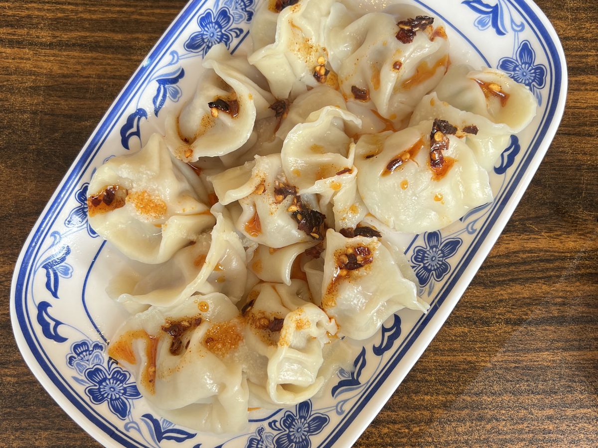 A decorative plate of a dozen dumplings topped with chili oil.